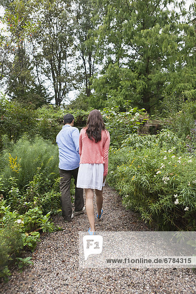 Rear view of couple walking through garden