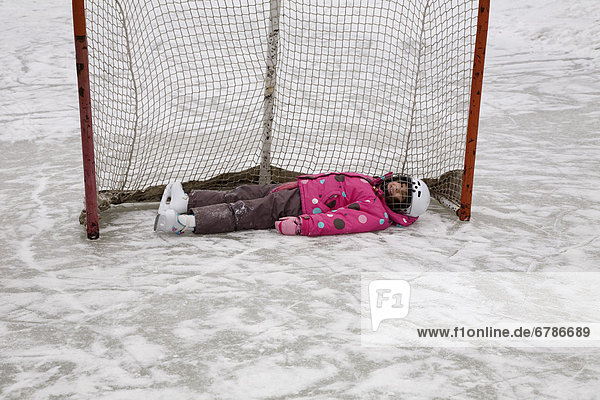 Young girl lying in a hockey net  Ontario