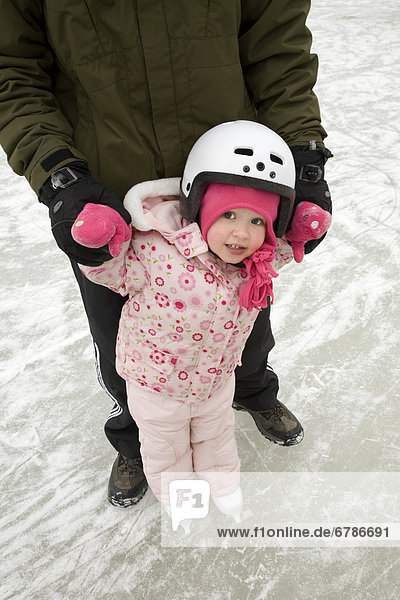 Dad teaching daughter to skate  Ontario