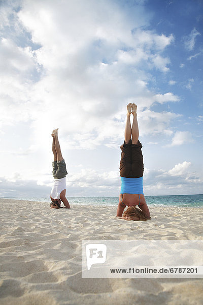Hawaii  Oahu  Lanikai  Young couple doing yoga  stay in a headstand position on the beach.