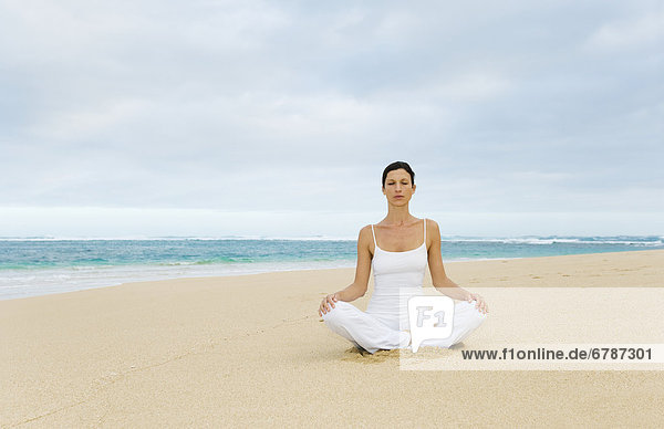 Hawaii  Frau meditieren am ruhigen Strand.