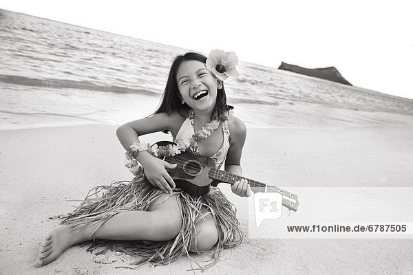 Hawaii  Oahu  junges Mädchen lächelnd und Ukulele am Strand im Hula Rock zu spielen.