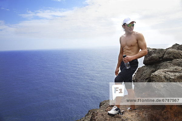 Hawaii  Oahu  Makapuu  Athletic male holding water bottle taking a break at Makapuu Cliffs