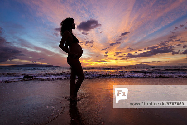 Hawaii  Pregnant woman on beautiful beach at sunset.