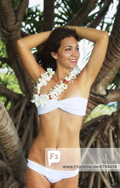 Hawaii  Oahu  Lanikai  schöne Mädchen steht auf einer Palme am tropischen Strand tragen eines weißes Outfit.