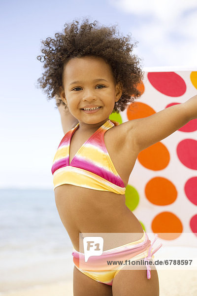 Hawaii  Oahu  Adorable little girl holding a polka-dot towel along the waters edge.