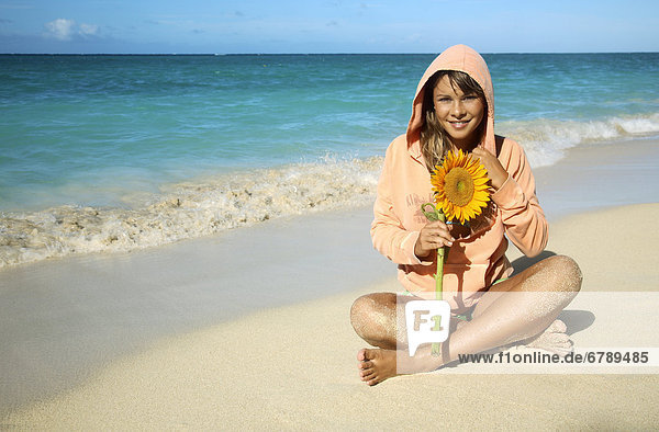 Hawaii  Oahu  Lanikai  attraktive junge Frau am Strand mit Sonnenblume.