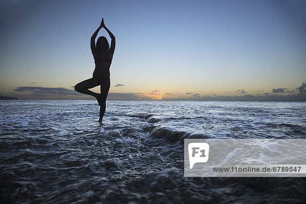 Hawaii  Oahu  Fit junges Mädchen am Strand doing Yoga auf der felsigen Küste.