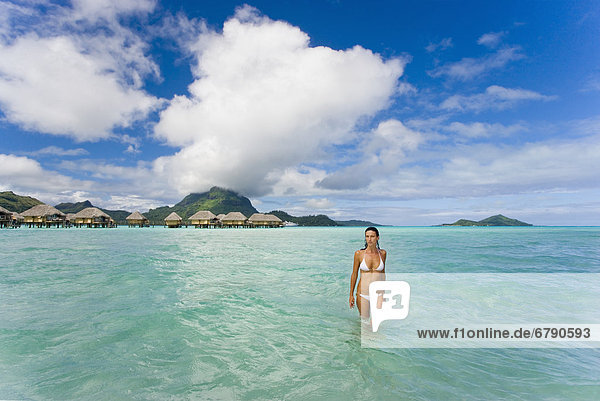 Französisch-Polynesien  Tahiti  Bora Bora  Frau im Ozean mit Bungalows im Hintergrund.