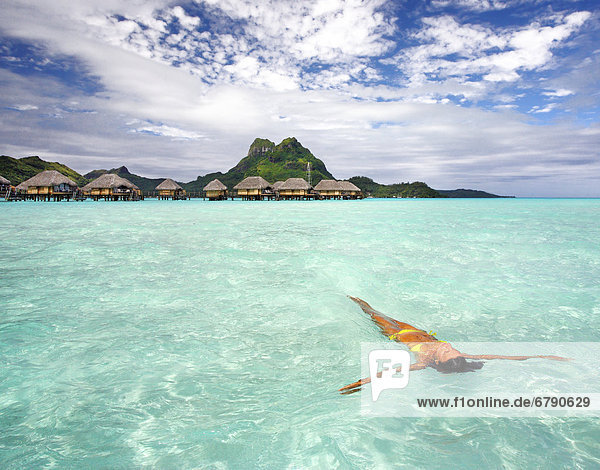 French Polynesia  Tahiti  Bora Bora  Woman floating in water near resort.