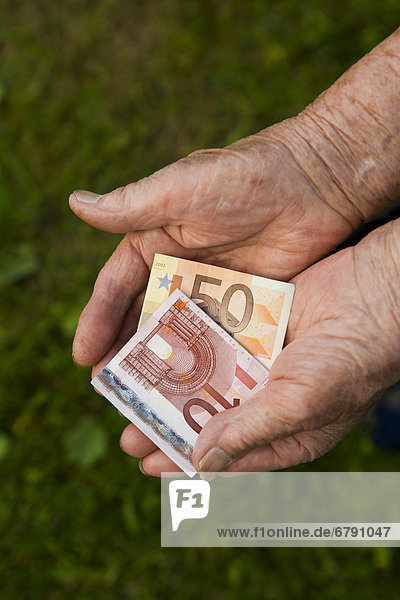 Alte Frau hält Geldscheine  Euro-Scheine in den Händen