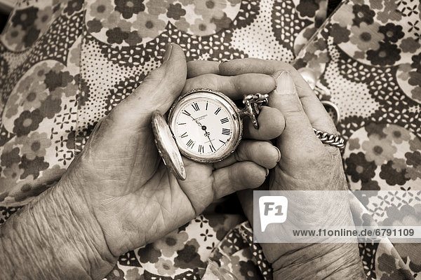 Alte Frau hält alte Taschenuhr in den Händen  Sepia-Bearbeitung