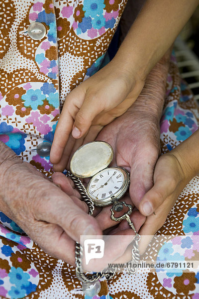 Alte Frau und Kind halten alte Taschenuhr in den Händen