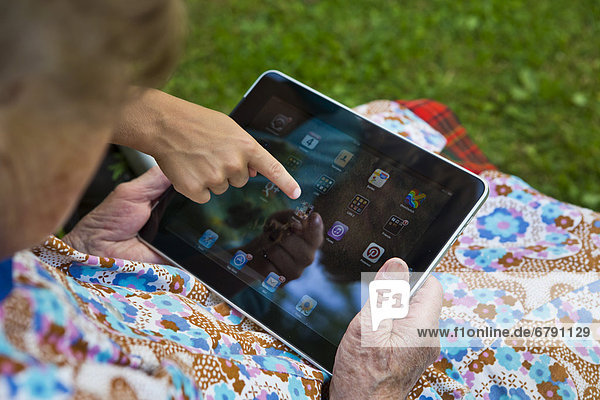 Kind zeigt alter Frau etwas auf einem Tablet-PC