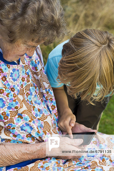 Kind zeigt alter Frau etwas auf einem Smartphone