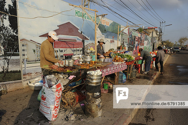 Garküche vor vietnamesischen Plakaten die für Projekte unter dem Namen des vietnamesischen Fußballvereins Ho‡ng Anh Gia Lai in Laos werben Vientiane Laos Südostasien Asien