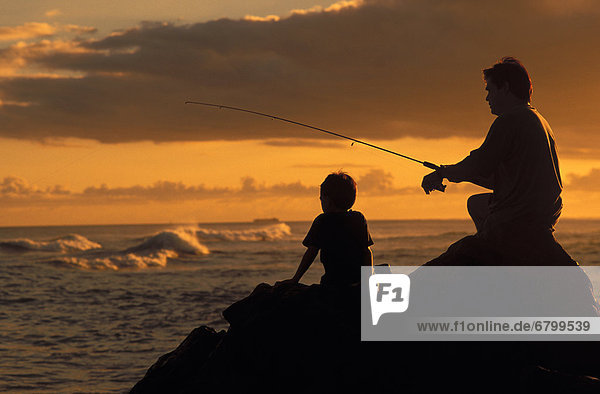 Local family  father and son fishing at sunset with dramatic foreground light