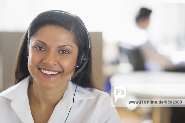 Businesswoman with headset  businessman in background