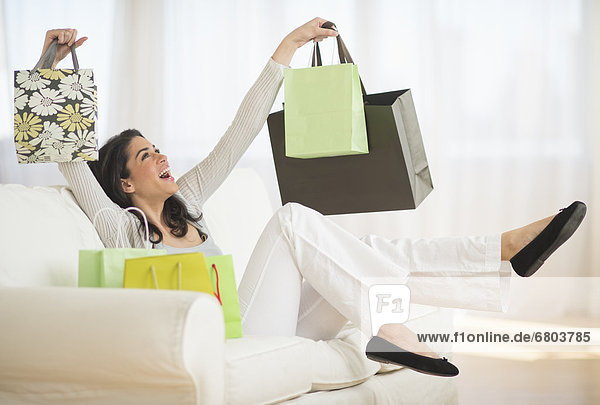 Young woman with shopping bags on sofa