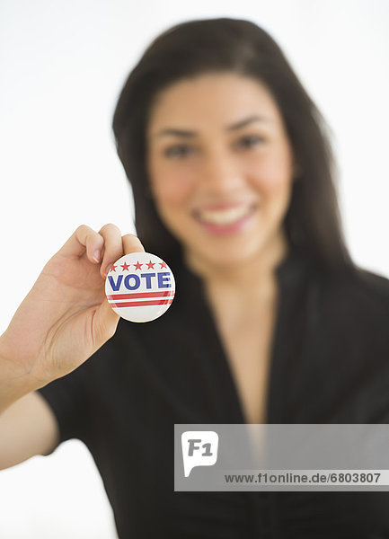 Studio portrait of young woman holding election badge