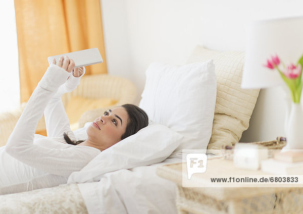 Young woman lying on bed using tablet pc