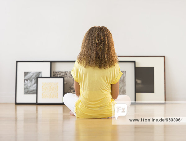 Woman sitting on floor looking at artworks