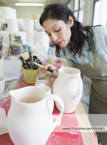 Female artist decorating pottery in studio