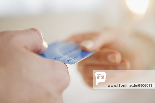 Close up of man's and woman's hands holding credit card