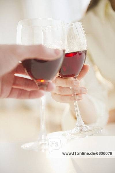 Close up of man's and woman's hands making toast with red wine