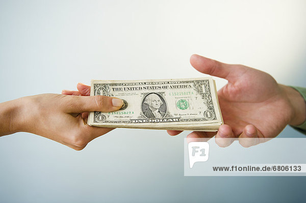Close up of man's and woman's hands holding banknotes  studio shot