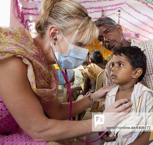 A Woman Wearing A Mask Using A Stethoscope On A Boy With His Father  Sathyamangalam  Tamil Nadu  India