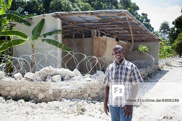 sitzend  Mann  Wand  Ruine  hoch  oben  frontal  Metalldraht  Stacheldraht  Haiti