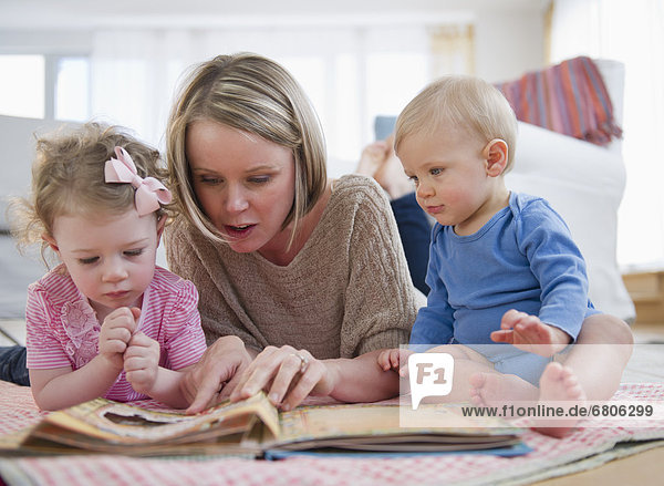 Mother with children (2-3  6-11 months) reading book