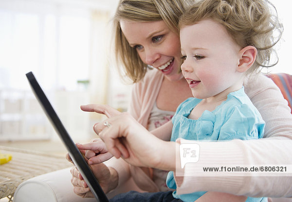 Mother with daughter (-11 months) using digital tablet at home