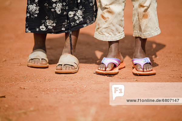 Two Pairs Of Feet Wearing Flip Flops On A Dusty Road  Kampala Uganda Africa