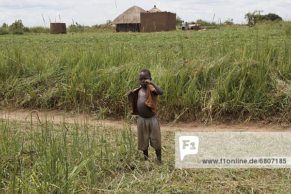 A Boy Standing On The Edge Of A Grass Field  Kampala Uganda Africa