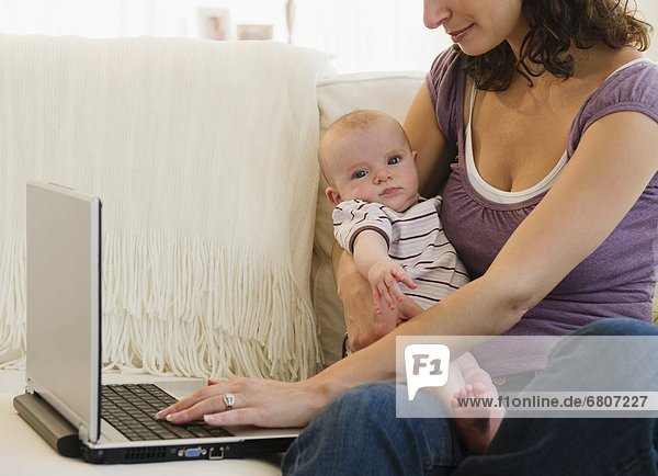 Mother with baby boy (2-5 months) using laptop