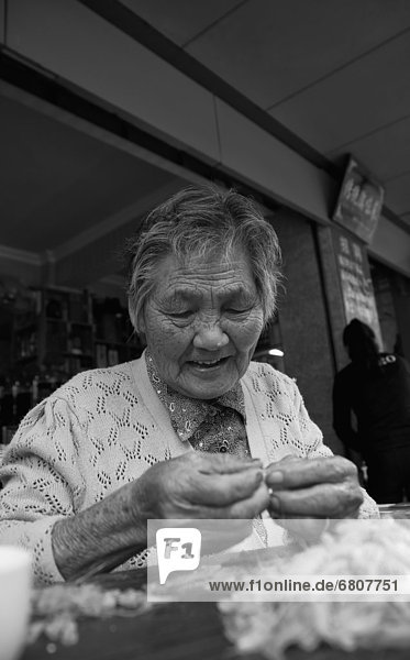 Senior  Senioren  Frau  sitzend  sticken  Reh  Capreolus capreolus  Tisch