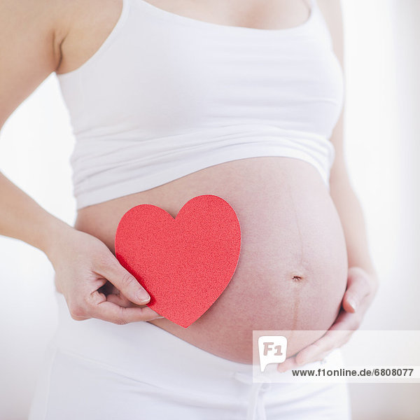 Frau  Papier  halten  Schwangerschaft  rot  herzförmig  Herz