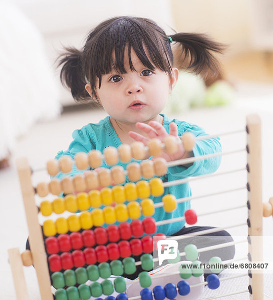 Portrait of baby girl (12-17 months) playing with abacus