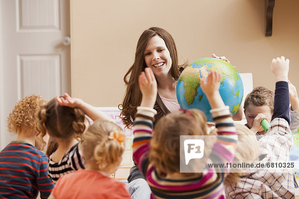 Geography teacher with children (2-3  4-5) raising hands