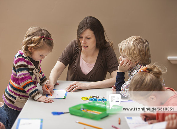 Mid adult woman teaching children (2-3  4-5) drawing in kindergarten