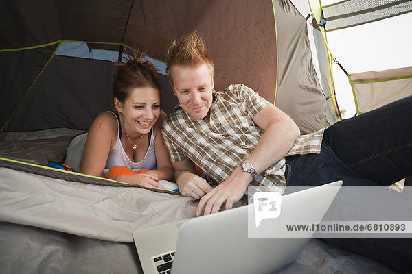 Hikers in tent using laptop