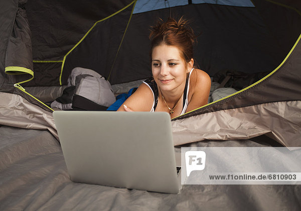 Hiker in tent using laptop