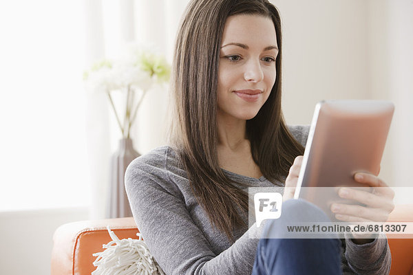 junge Frau junge Frauen benutzen Couch lächeln Tablet PC