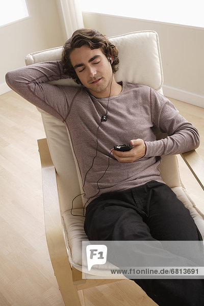 Young man listening music on armchair