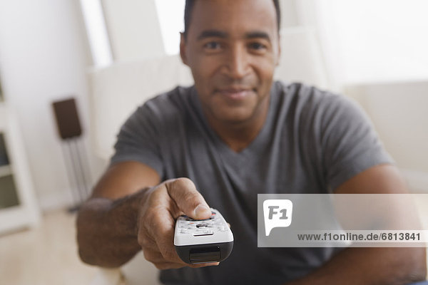 Mature man holding remote control  focus on foreground