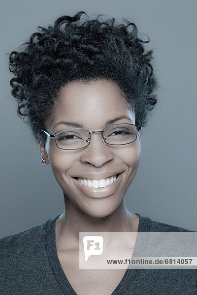 Studio shot of young woman smiling wearing glasses