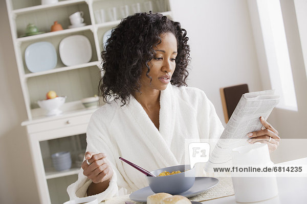 Frau Mittelpunkt essen essend isst Erwachsener Frühstück Zeitung vorlesen
