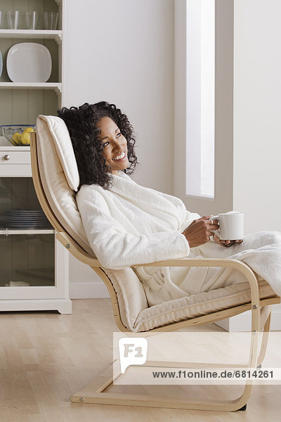 Woman drinking coffee in armchair in morning